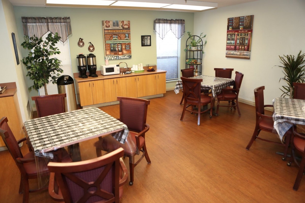 A cozy caf interior with tables and chairs, a coffee station, and wooden flooring.