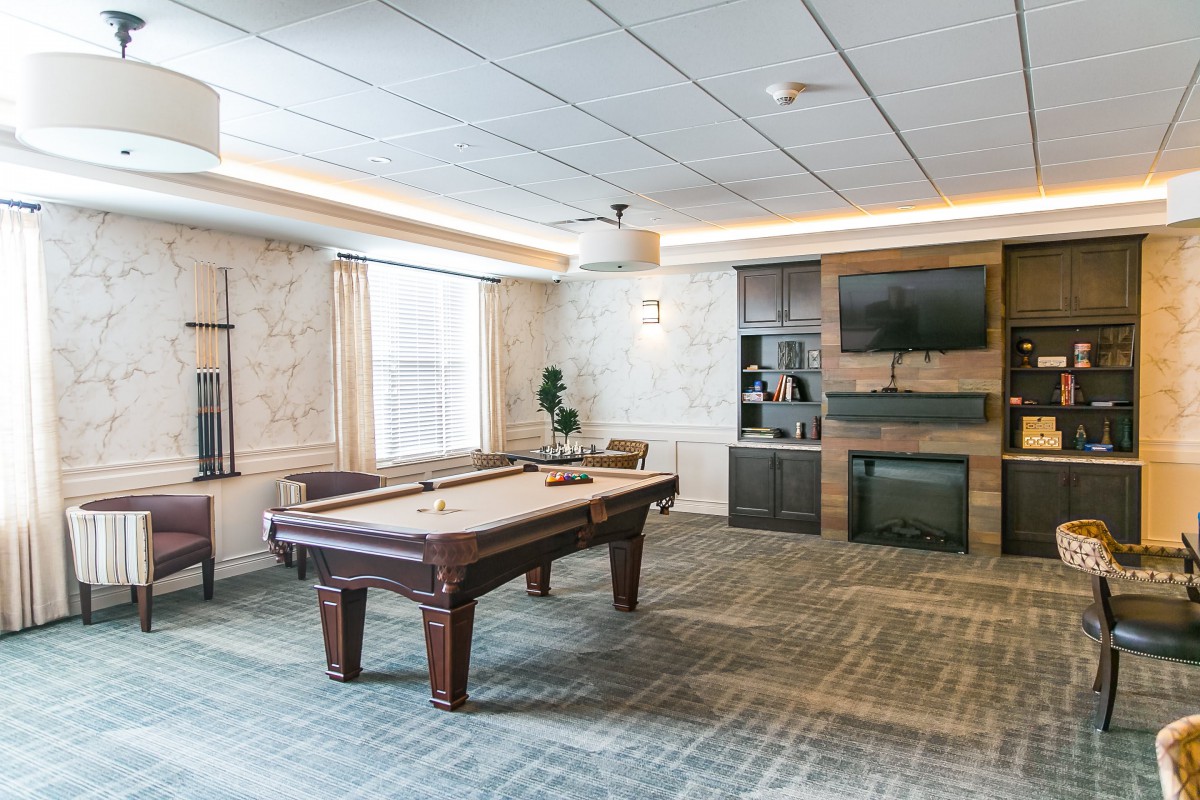 A modern game room featuring a pool table, television, and fireplace.