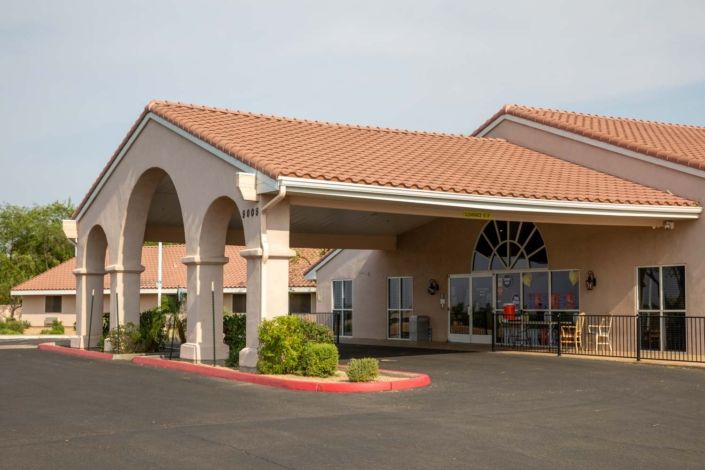 A hotel entrance with arched design and well-maintained landscaping.
