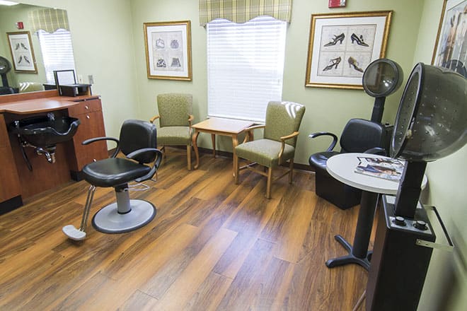 A cozy waiting area in a salon with a barber chair and comfortable seating.