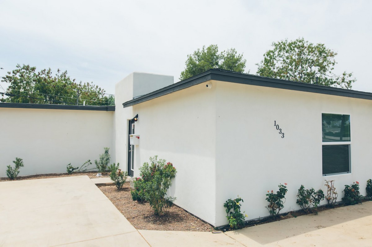 A modern minimalist house with a simple landscape and driveway.