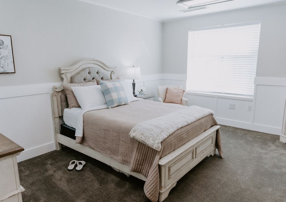 A cozy bedroom with a neatly made bed, featuring soft neutral tones and elegant decor.