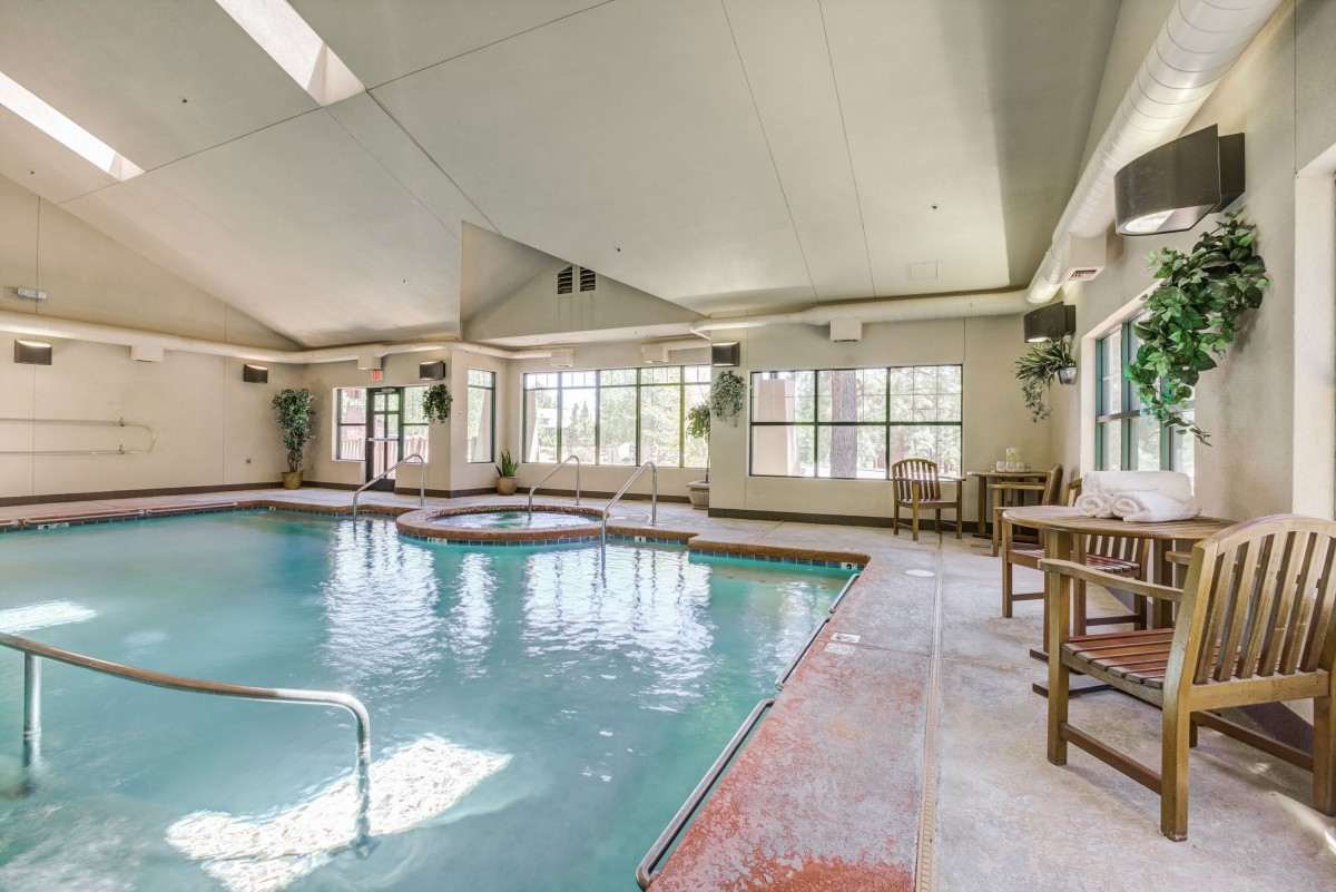 An inviting indoor swimming pool with ample natural lighting and comfortable seating for relaxation.