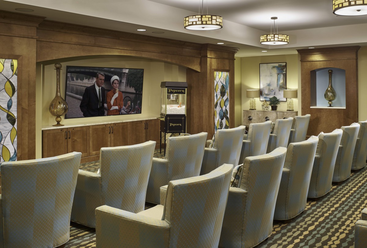 A modern home theater room with rows of comfortable chairs and a large screen.