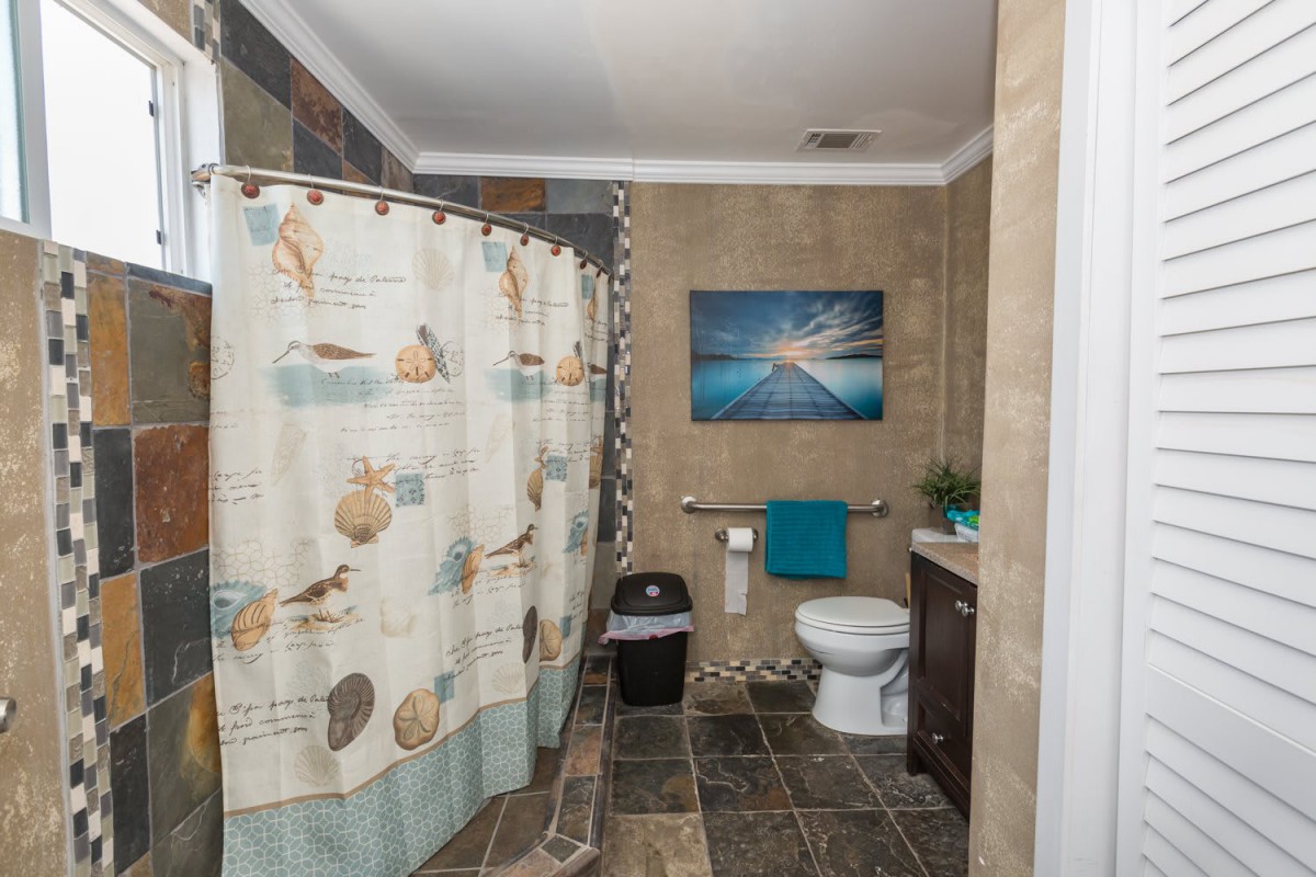 A neatly arranged bathroom with a coastal-themed shower curtain and artwork.