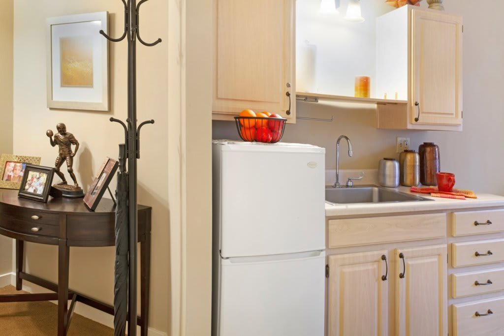 A compact kitchen area with a refrigerator, sink, and wooden cabinets.