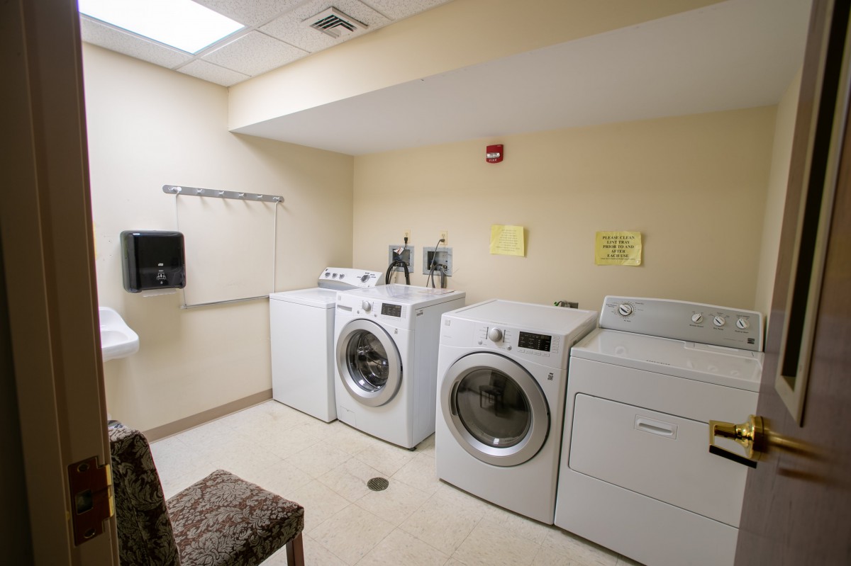 A laundry room with washing machines and a dryer lined up against the wall.