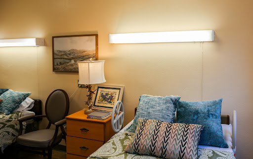 A cozy bedroom setup featuring a bed adorned with decorative pillows, a bedside lamp, and a chair.