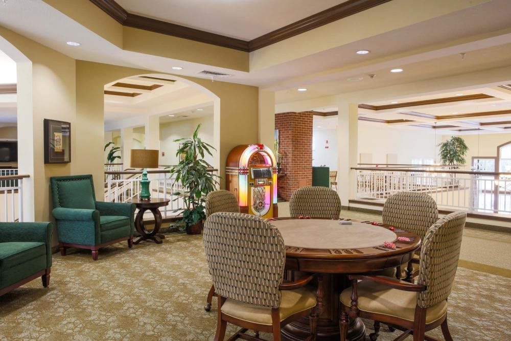 A cozy seating area featuring a classic jukebox and a round table with chairs, complemented by warm lighting and potted plants.