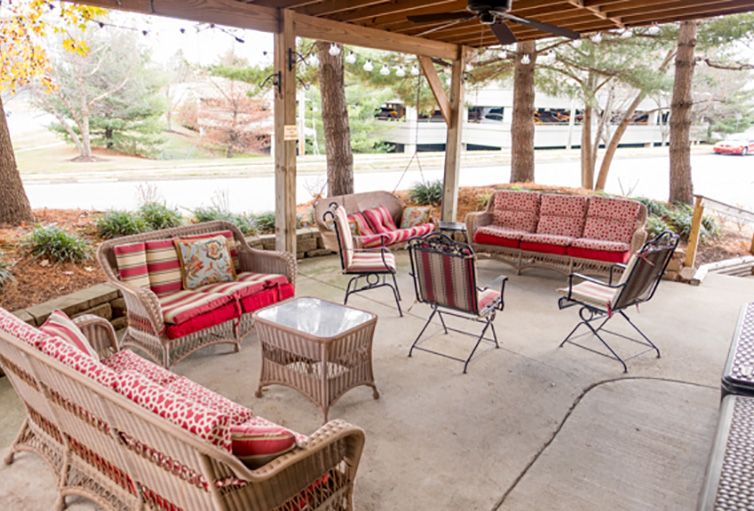 A cozy covered patio area with rattan furniture and red cushions.