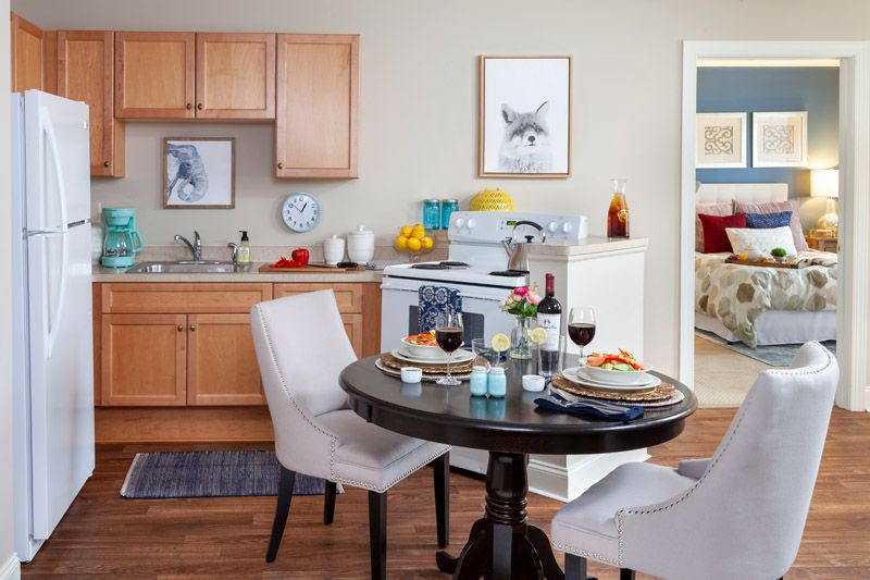 A cozy apartment kitchen with a dining table set for two and light wood cabinets.