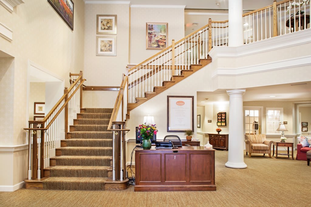 A hotel lobby featuring a grand staircase and a reception desk.