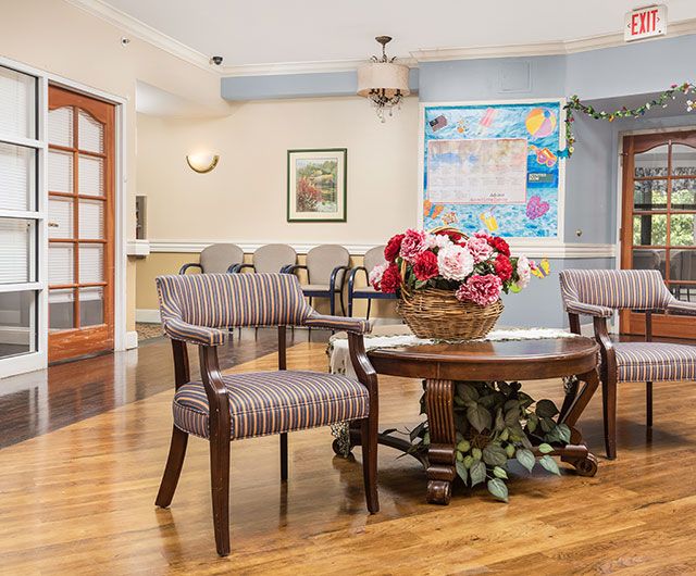 A cozy waiting room with comfortable chairs and a floral centerpiece on a wooden table.
