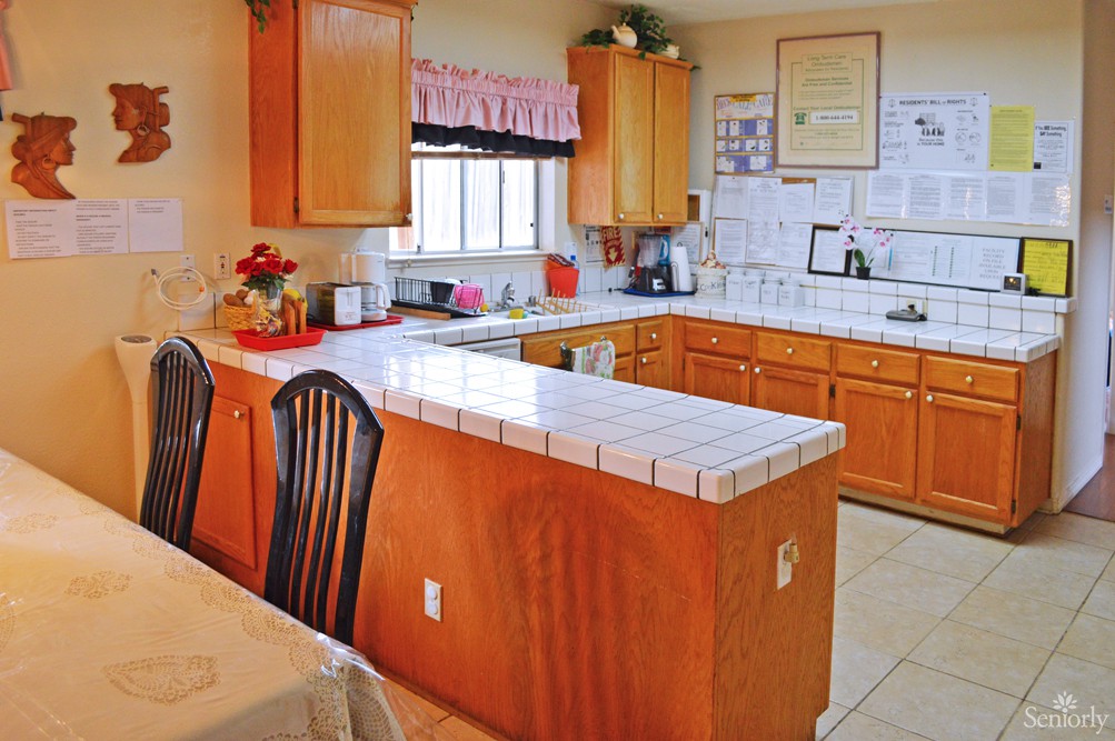 A cozy kitchen with wooden cabinets and a tiled countertop.