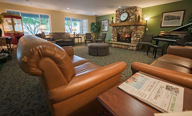 A cozy living room with a leather sofa and a stone fireplace, featuring a large clock and elegant interior design.