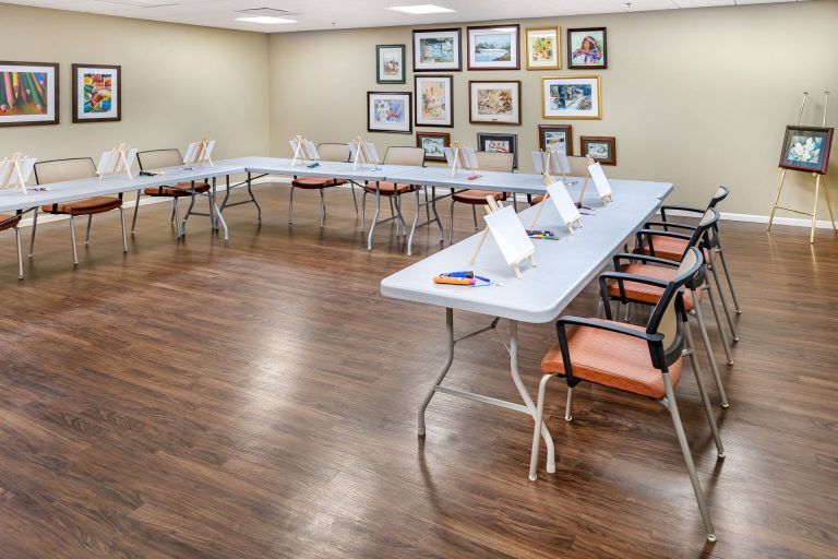 An empty meeting room with U-shaped table arrangement, featuring artwork on the walls and a wooden floor.