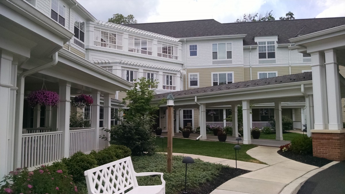 A well-maintained residential building with a spacious courtyard and benches, surrounded by greenery.