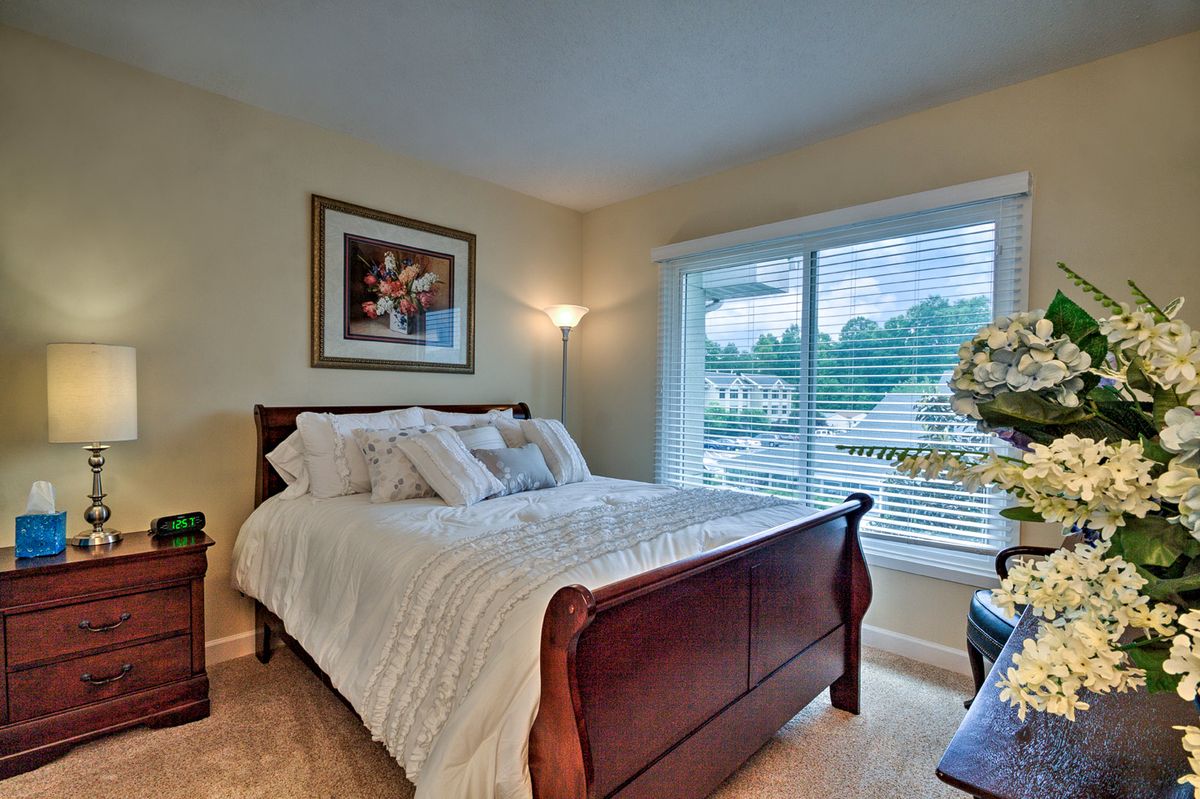 A cozy bedroom with a wooden bed, large window, and decorative elements.