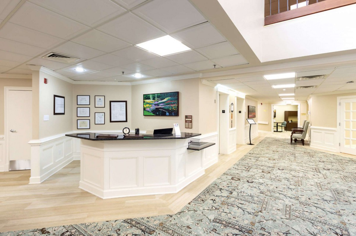 A modern reception area with a desk and a carpeted hallway.