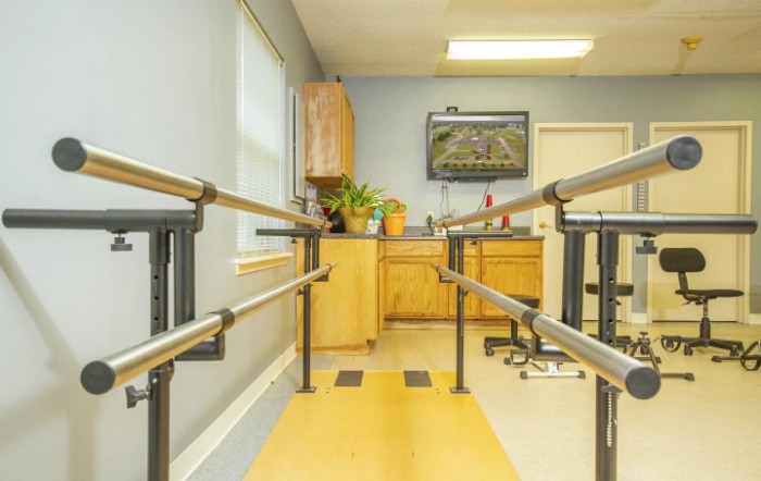 A physical therapy room featuring parallel bars used for rehabilitation exercises.
