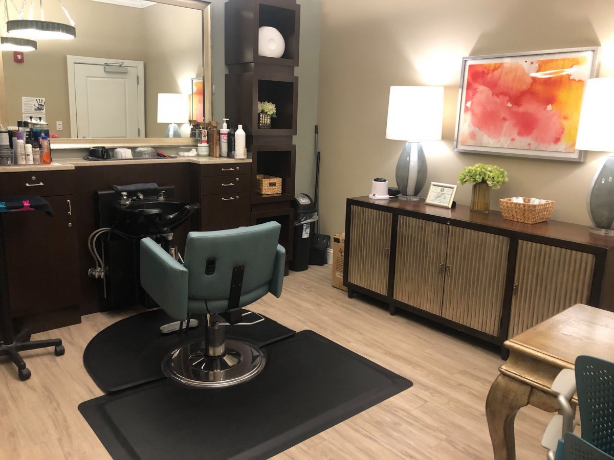 A cozy and well-lit hair salon with a styling chair and mirror.