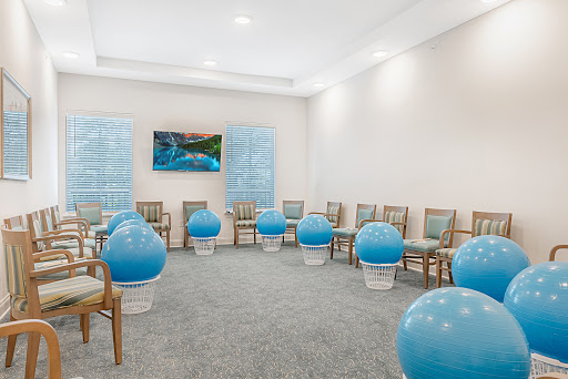 A modern waiting room featuring blue exercise balls and comfortable chairs, designed for relaxation.