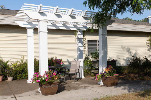 A peaceful outdoor setting featuring a white pergola surrounded by colorful flower planters.