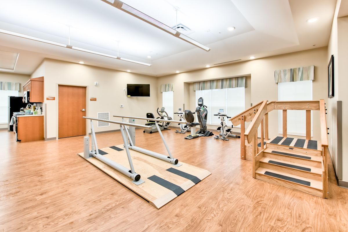 A well-equipped rehabilitation center with exercise equipment, parallel bars, and stairs for physical therapy.