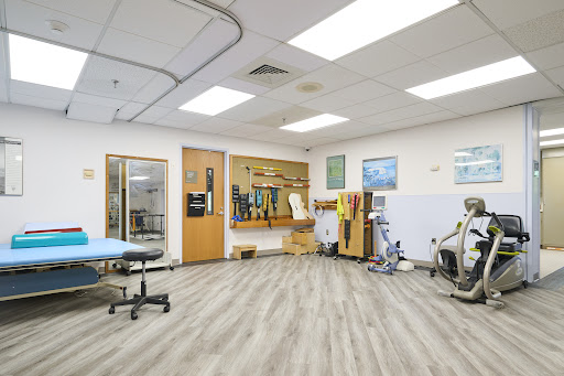 A spacious physical therapy clinic featuring various exercise equipment and treatment areas.