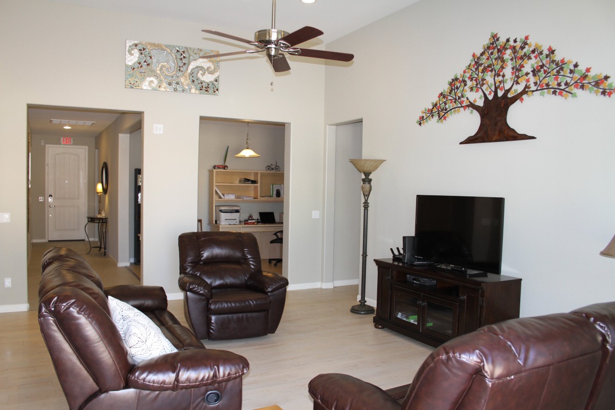 A cozy living room featuring leather furniture, a flat-screen TV, and elegant wall decor.