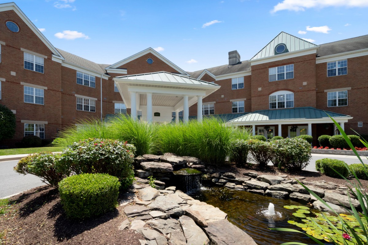A beautifully landscaped residential building with a pond and lush greenery.