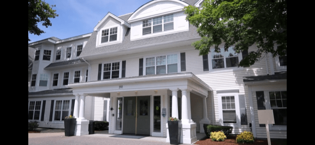 A two-story residential building with a white exterior and multiple windows.