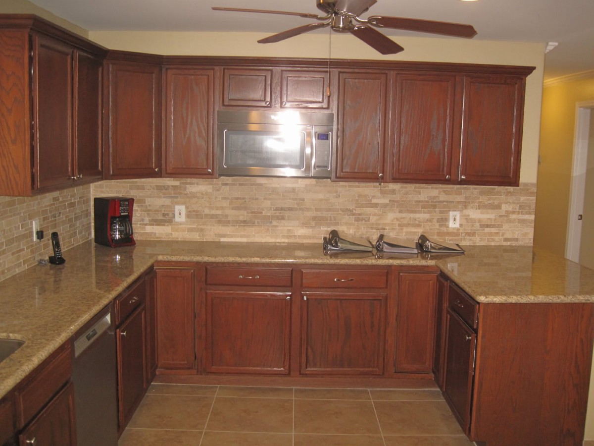 A kitchen with wooden cabinets, a microwave, and a tiled floor.