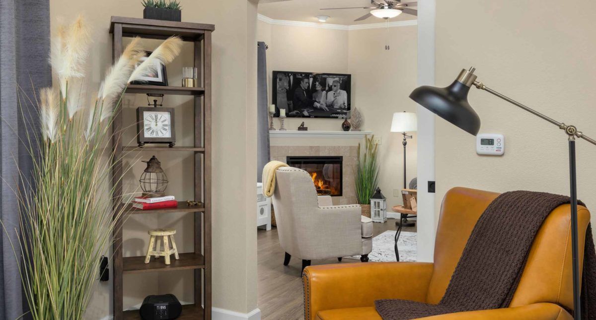 A cozy living room with a fireplace, armchair, and bookshelf, showcasing modern interior design.