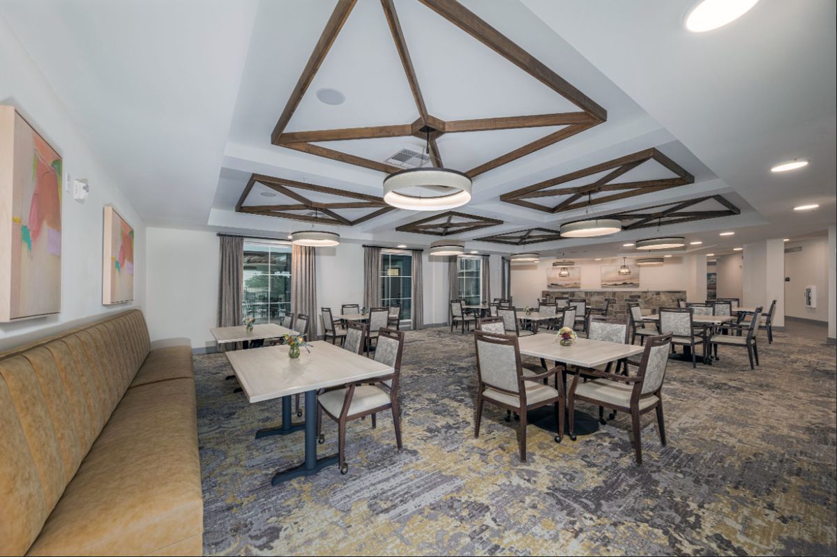 A modern dining room with elegantly designed furniture and decorative ceiling beams.