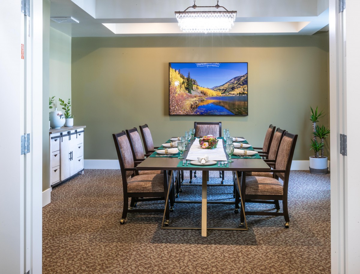 A well-decorated dining room featuring a large table with chairs and a landscape painting on the wall.