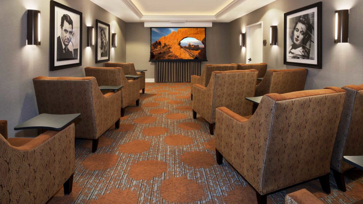 A cozy theater room with comfortable seating facing a large screen.