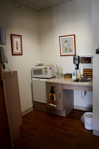 A cozy kitchen space featuring a microwave, sink, and decorative artwork on the walls.