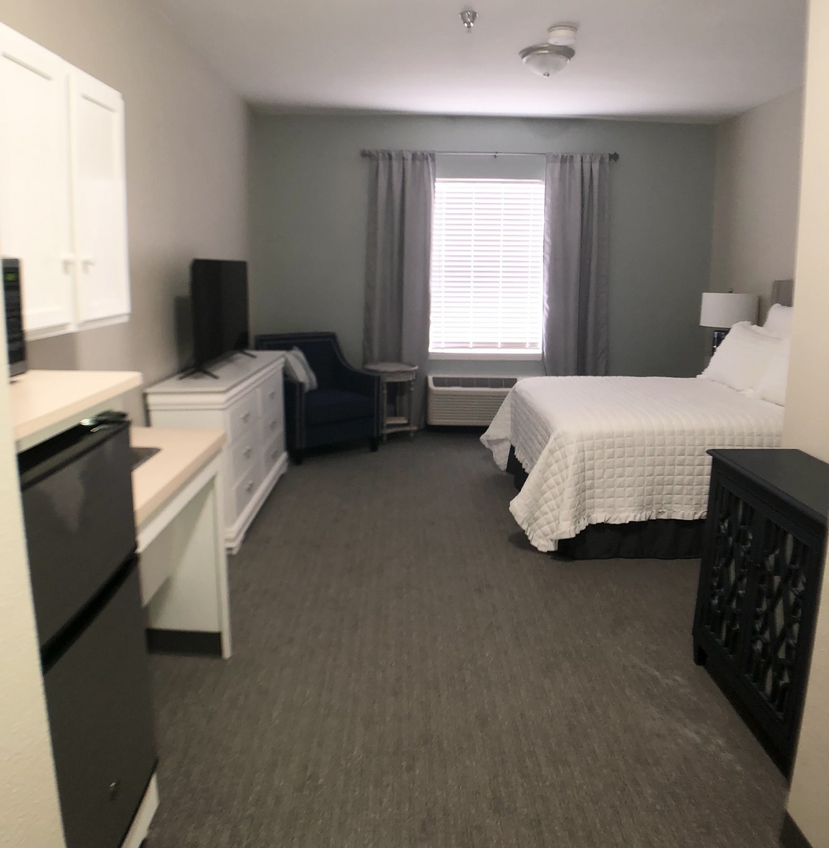 A minimalistic hotel room with a bed, window, and essential furniture.