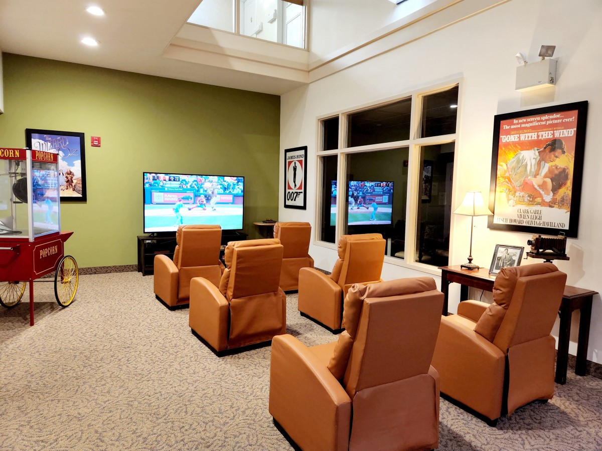 A cozy lounge with comfortable chairs facing a large television, perfect for relaxing or waiting.