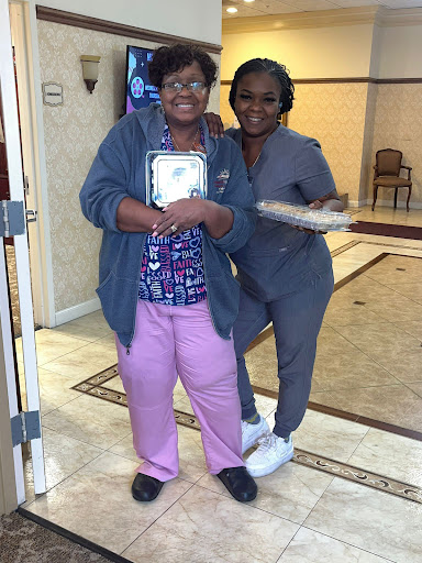 A joyful moment shared between a caregiver and an elderly woman, celebrating together.