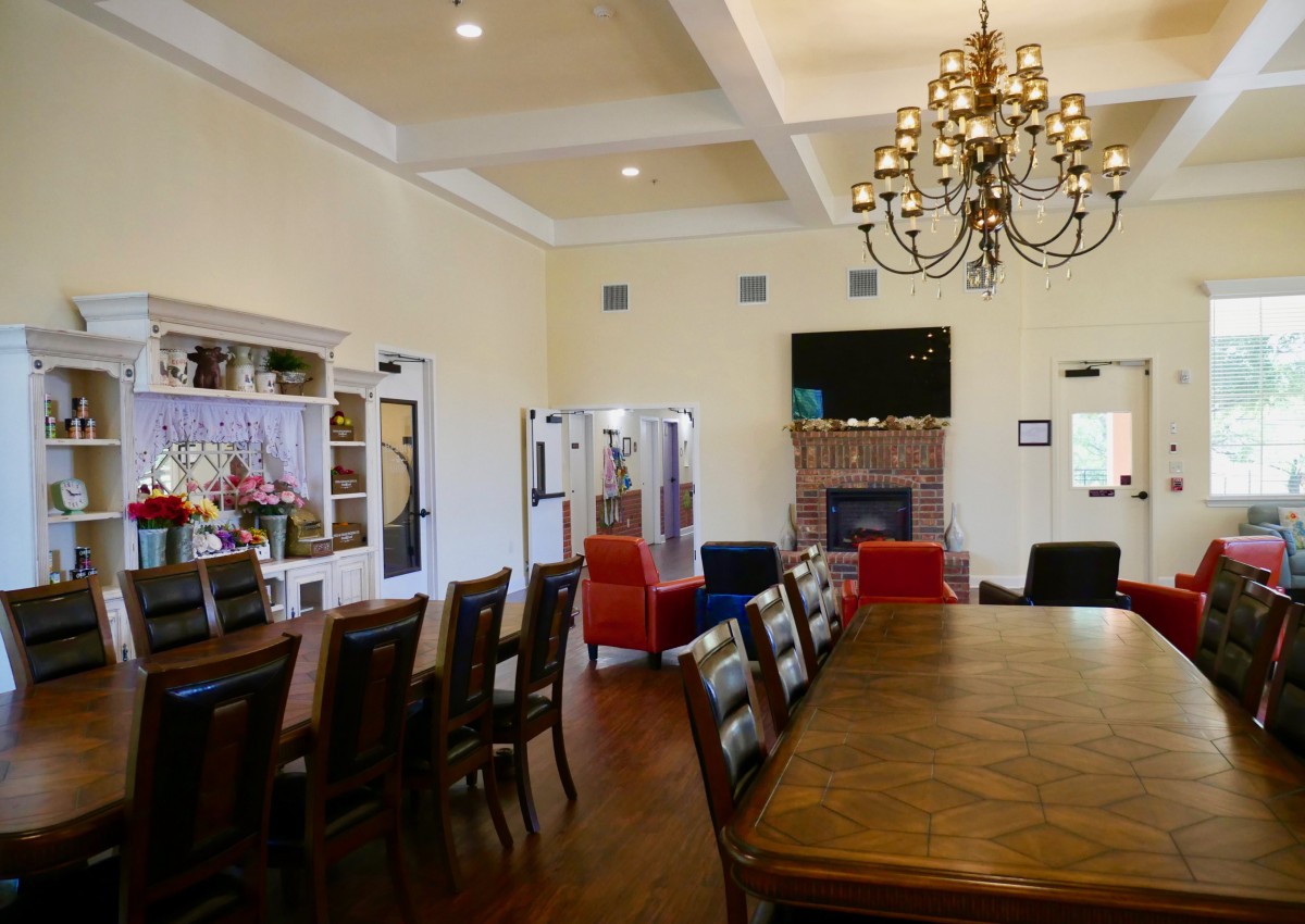 Elegant living and dining area featuring a large table, chandelier, and fireplace.