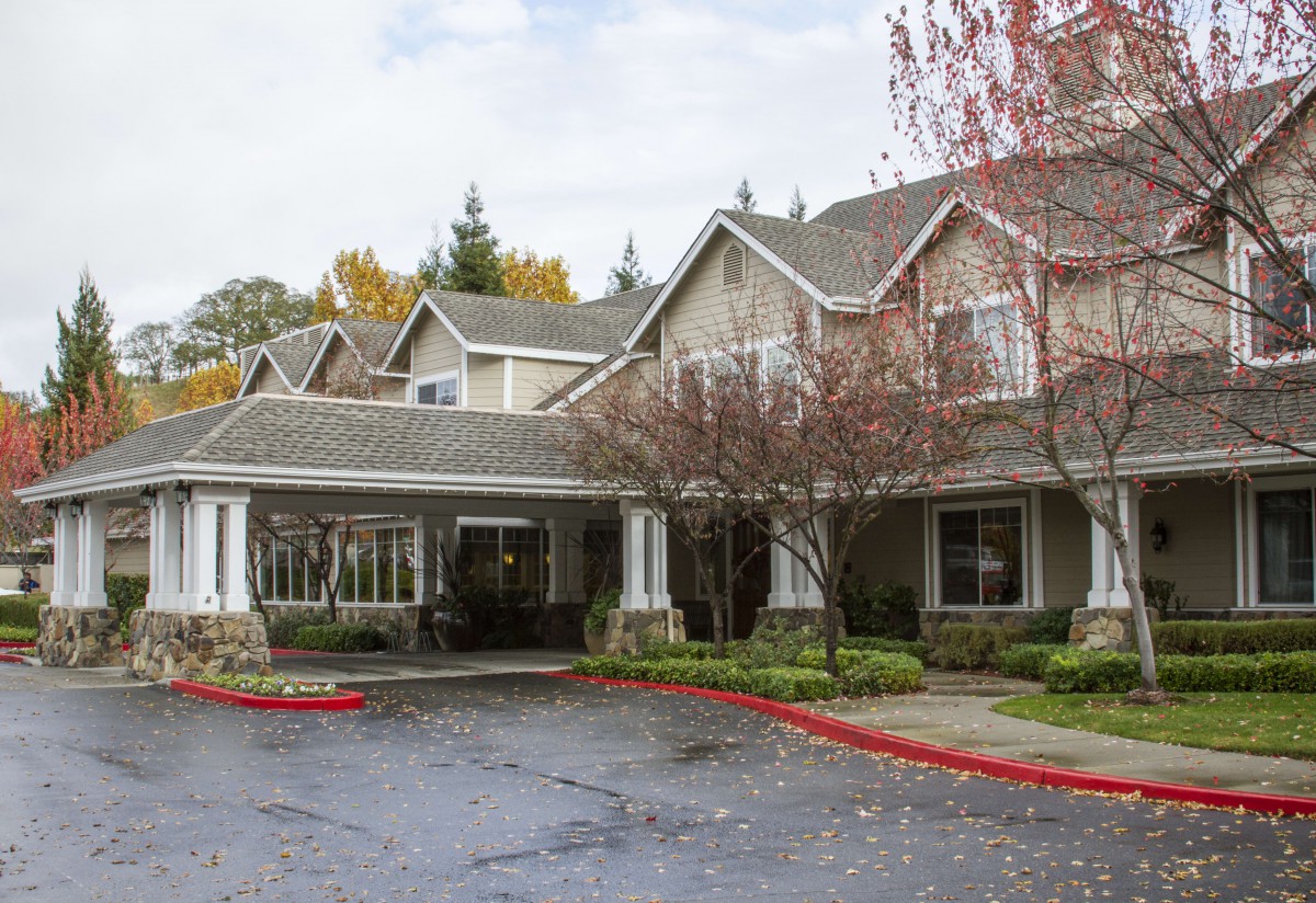 A residential building with a driveway and surrounding trees.