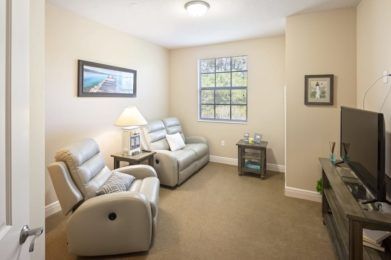 A cozy living room with recliner chairs, a window, and decorative artwork.