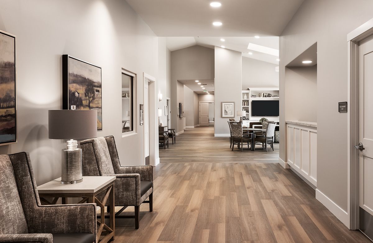 A modern hallway with wooden flooring and stylish furniture, adorned with artwork on the walls.