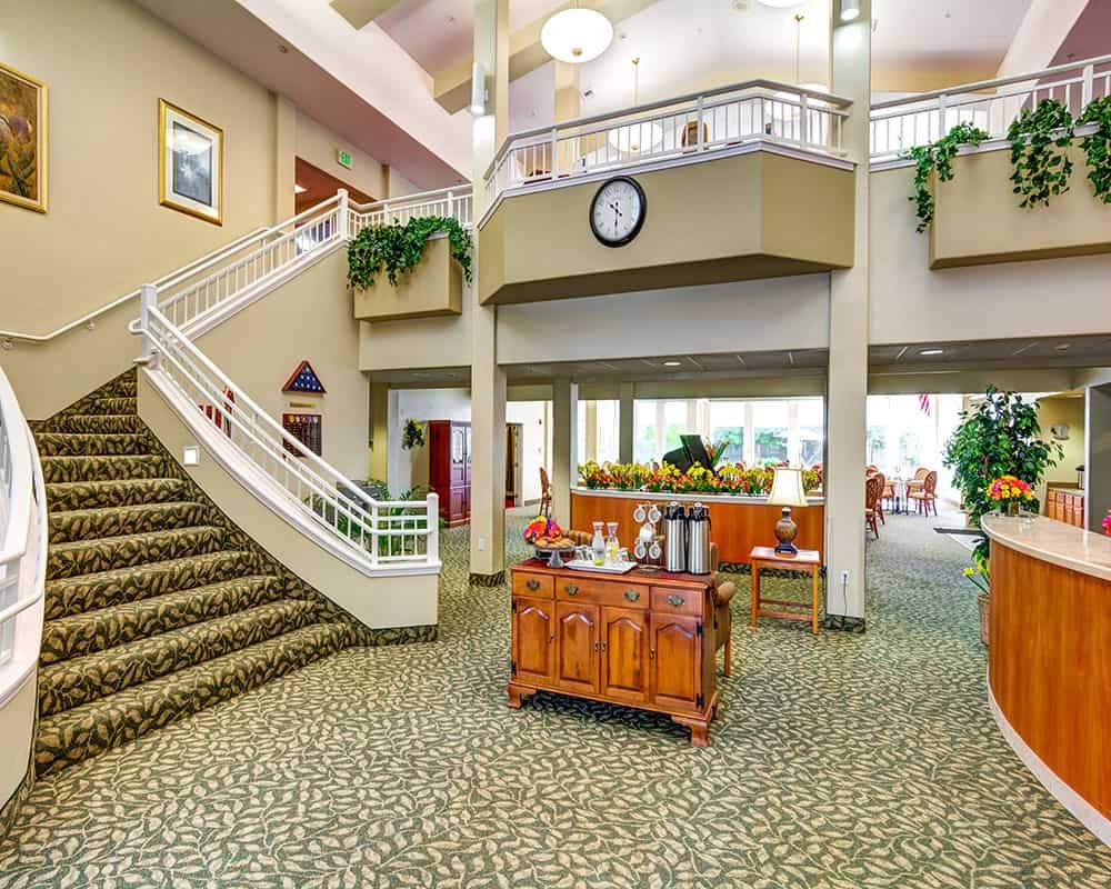 A spacious lobby with a staircase, decorative plants, and comfortable furnishings.