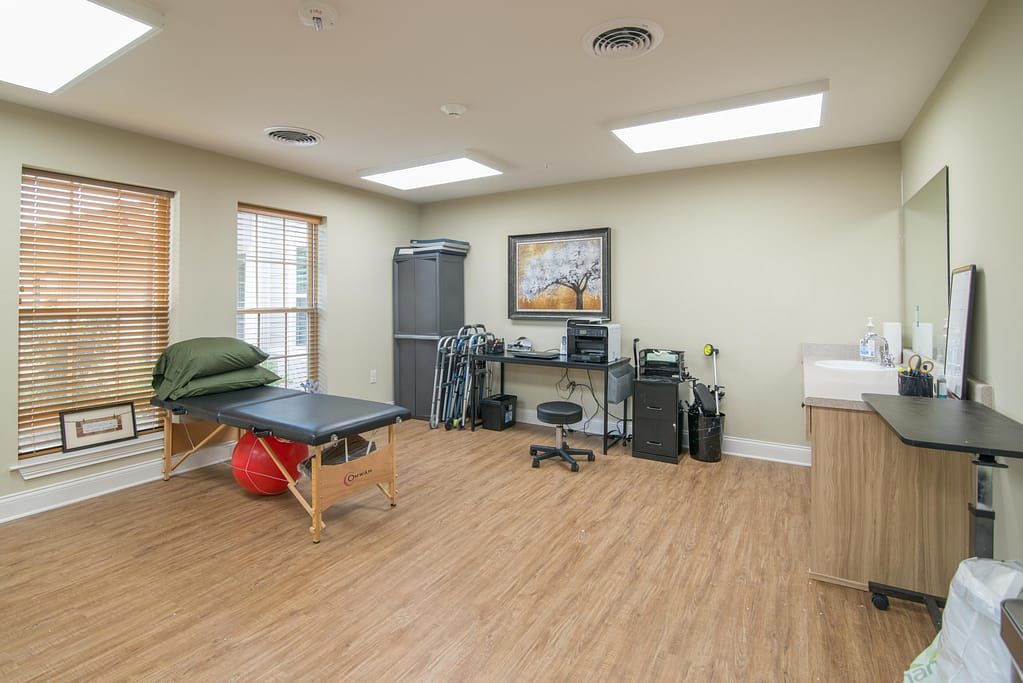 A spacious medical office equipped with an examination table and various therapy tools.