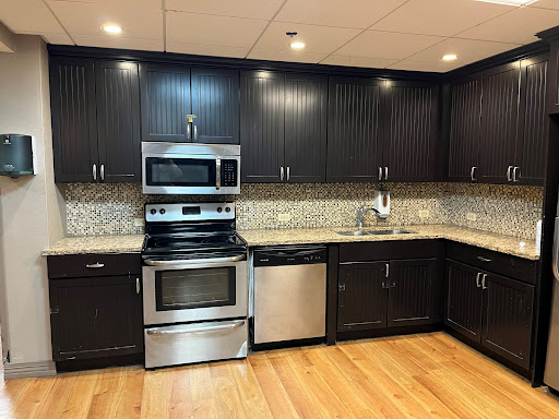 A modern kitchen featuring sleek black cabinets, stainless steel appliances, and a stylish granite countertop.