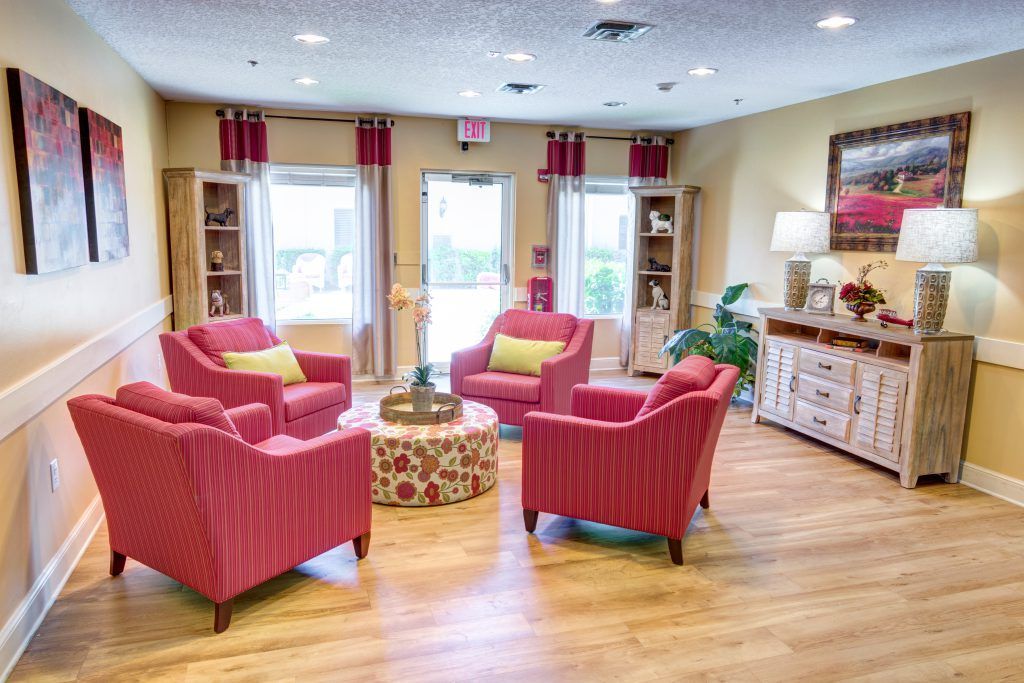 A bright and cozy living room with modern decor, featuring red armchairs and a central coffee table.