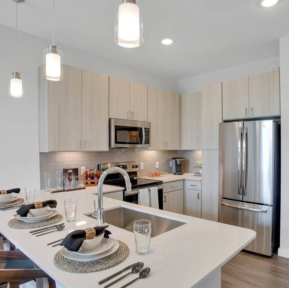 A modern kitchen with sleek appliances, a large island with bar seating, and elegant pendant lighting.